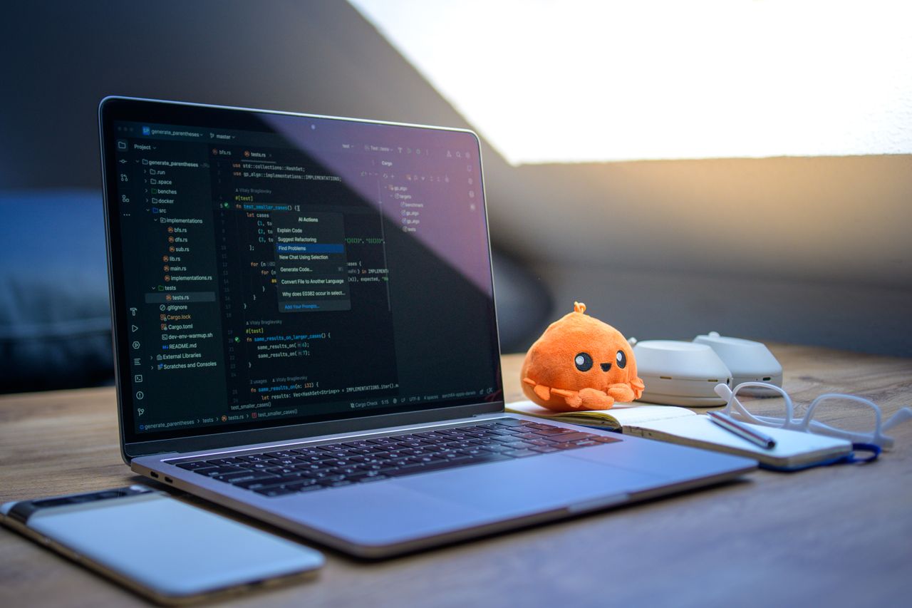 Crafting Captivating Headlines: Your awesome post title goes here A cozy workspace featuring a laptop displaying code, a smartphone, and a cute orange plush toy on the desk.